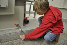 Kind zapft frisches Trinkwasser aus einem Hahn im Wasserwerk Lobberich
